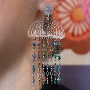 Glittery Acrylic jellyfish earrings with rainbow star chain, being modelled. 