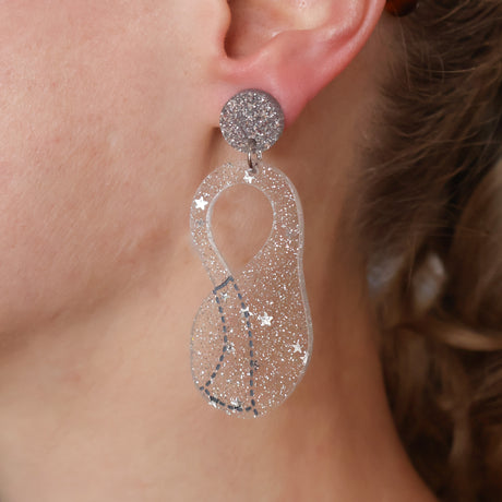 Close-up of a person wearing sparkling silver Klein flask earrings.