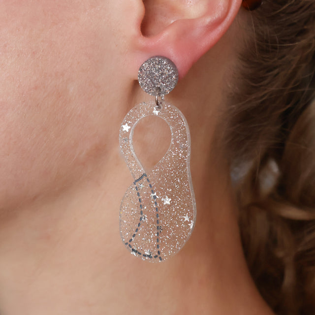 Close-up of a person wearing sparkling silver Klein flask earrings.