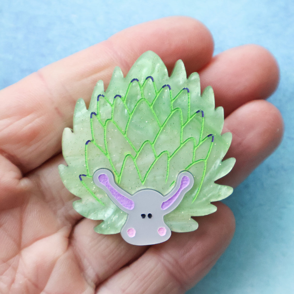 Closeup of green leaf sheep acrylic brooch held in a hand
