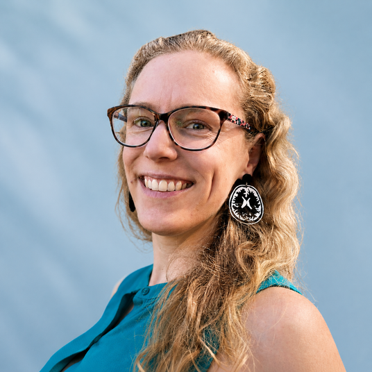 Maker Louise van der Werff modelling a pair of MRI brain earrings  against a blue background.