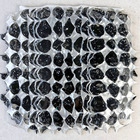 A melt pressed recycled acrylic sheet comprising of black and pearlescent acrylic scraps pressed within. Moon phase shapes are present. 