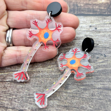 A pair of acrylic neuron earrings showing the nucleus and myelin sheath