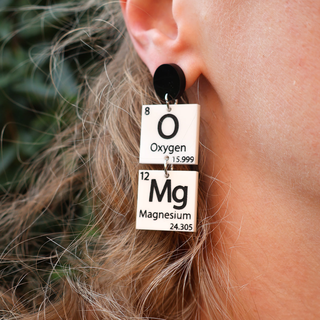 Black and white OMg periodic table earrings being modelled. 