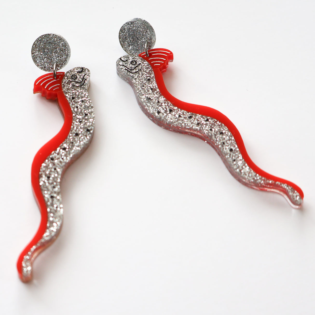 Red and silver glitter oarfish acrylic dangle earrings viewed at an angle