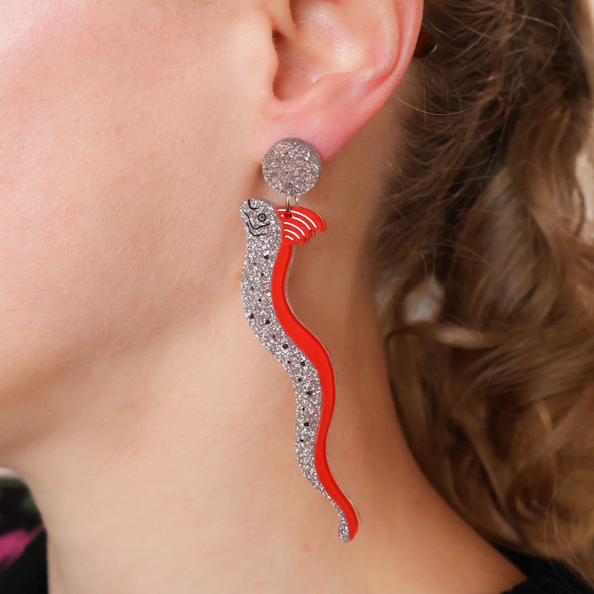Earring with red and silver oarfish design worn by a person