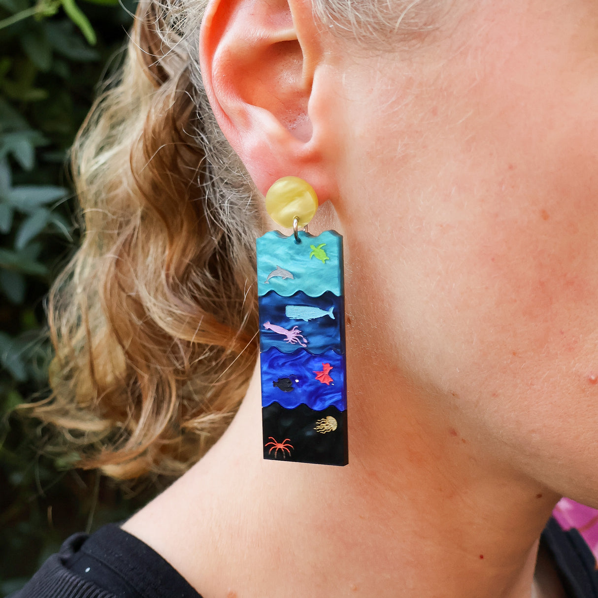Earring with ocean-themed design worn by a person outdoors