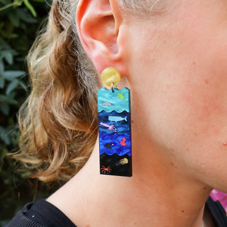 Earring with ocean-themed design worn by a person outdoors