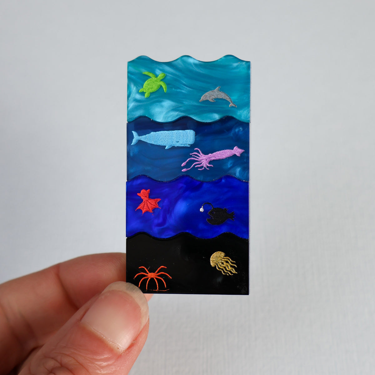Ocean zones brooch being held up