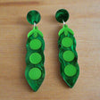 Green pea pod earrings on a gray background