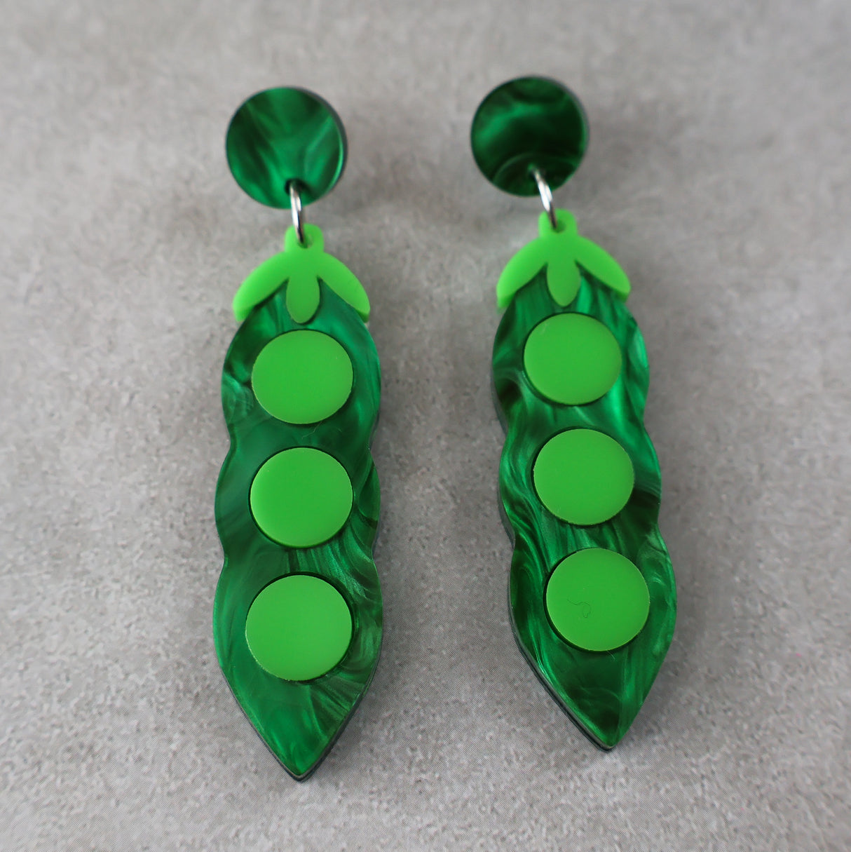 Green pea pod earrings on a gray background