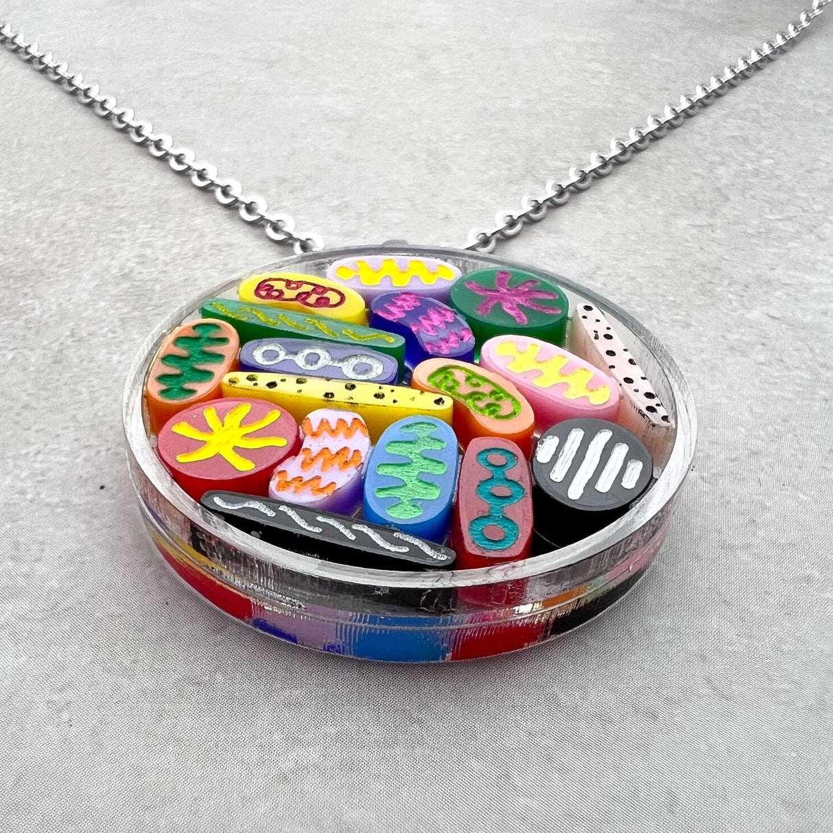 Necklace with colorful Petri dish acrylic pendant on a gray background