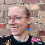 A woman modelling a pair of medicine pill earrings in blue and red