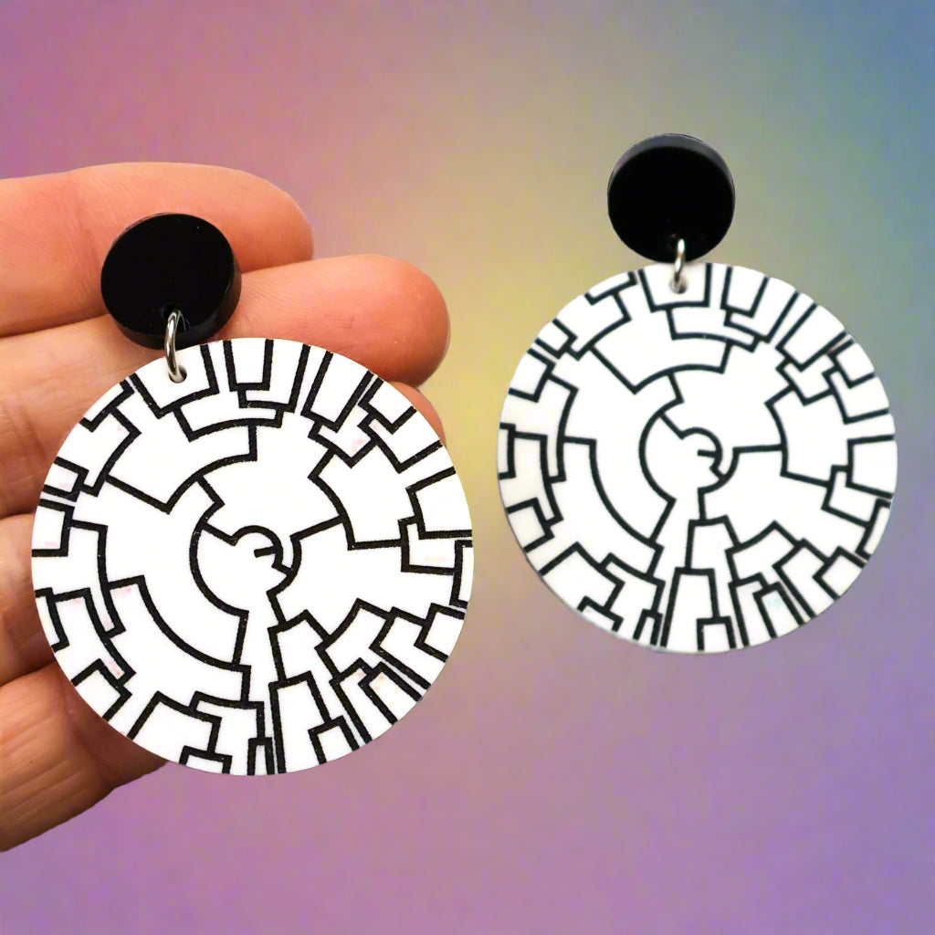 Round white dangle earrings with a black phylogenetic tree designed etched within. Hanging from black round acrylic toppers. 