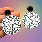 Round white dangle earrings with a black phylogenetic tree designed etched within. Hanging from black round acrylic toppers. 