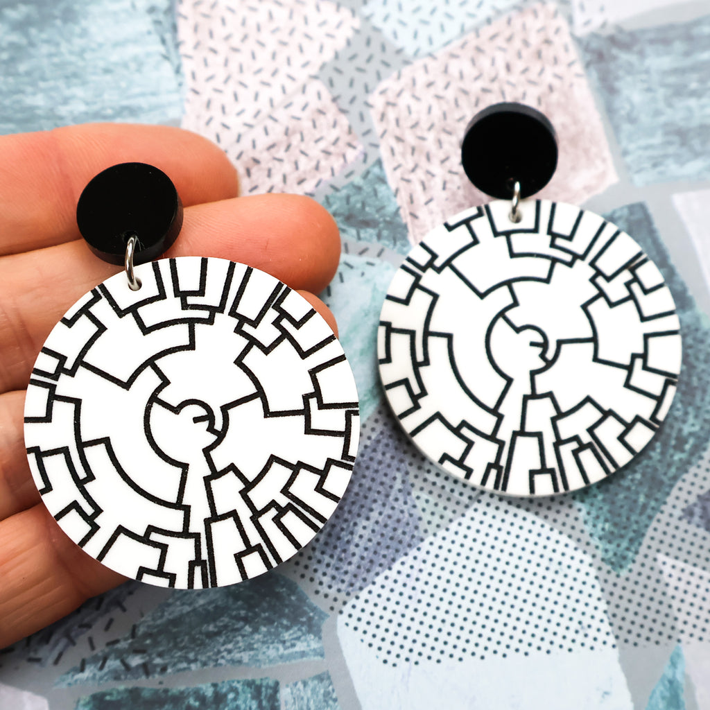 Round white dangle earrings with a black phylogenetic tree designed etched within. Hanging from black round acrylic toppers. 