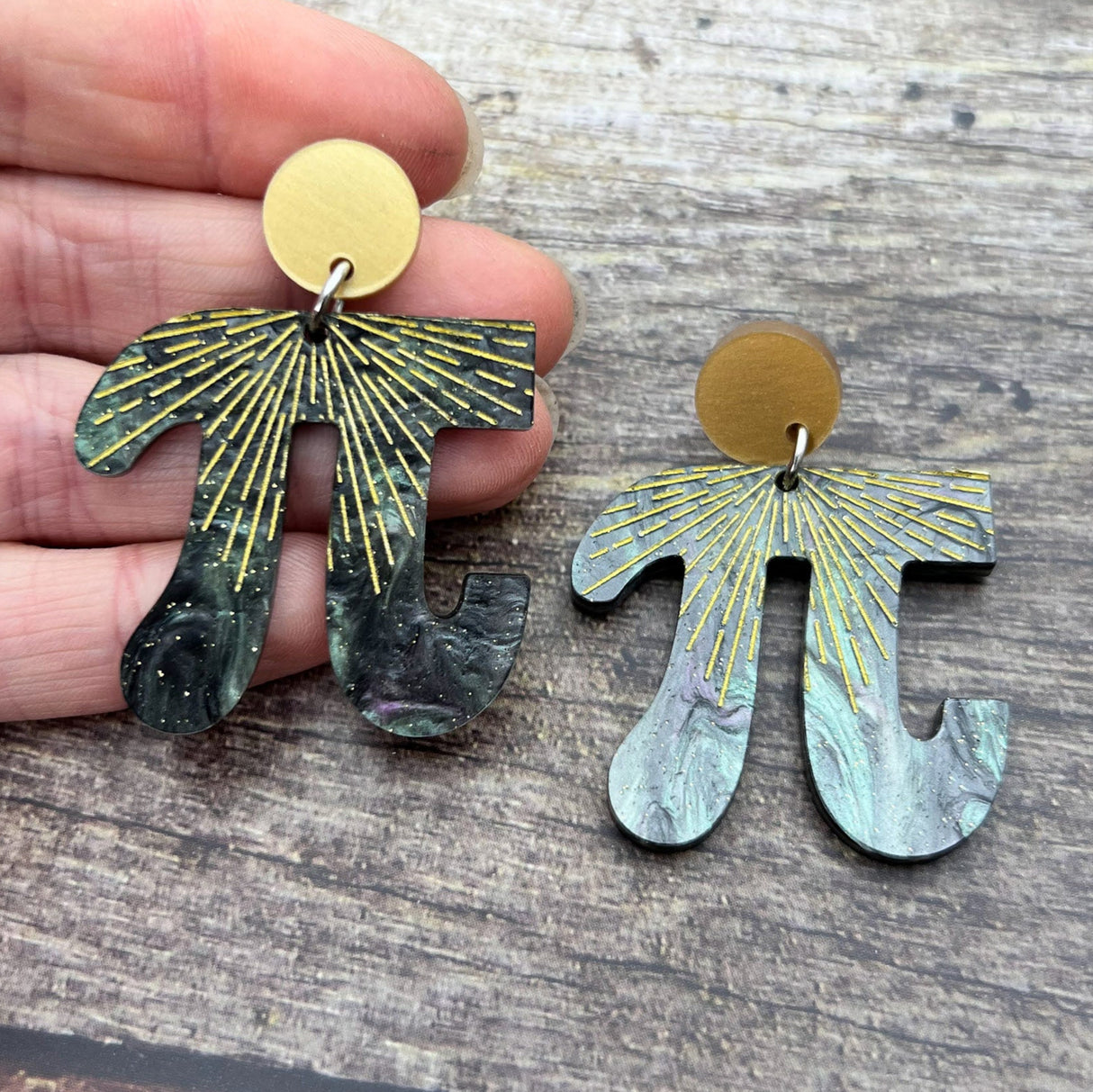 Acrylic Pi shaped earrings, with a starburst pattern. Hanging from gold toned acrylic earring toppers. 