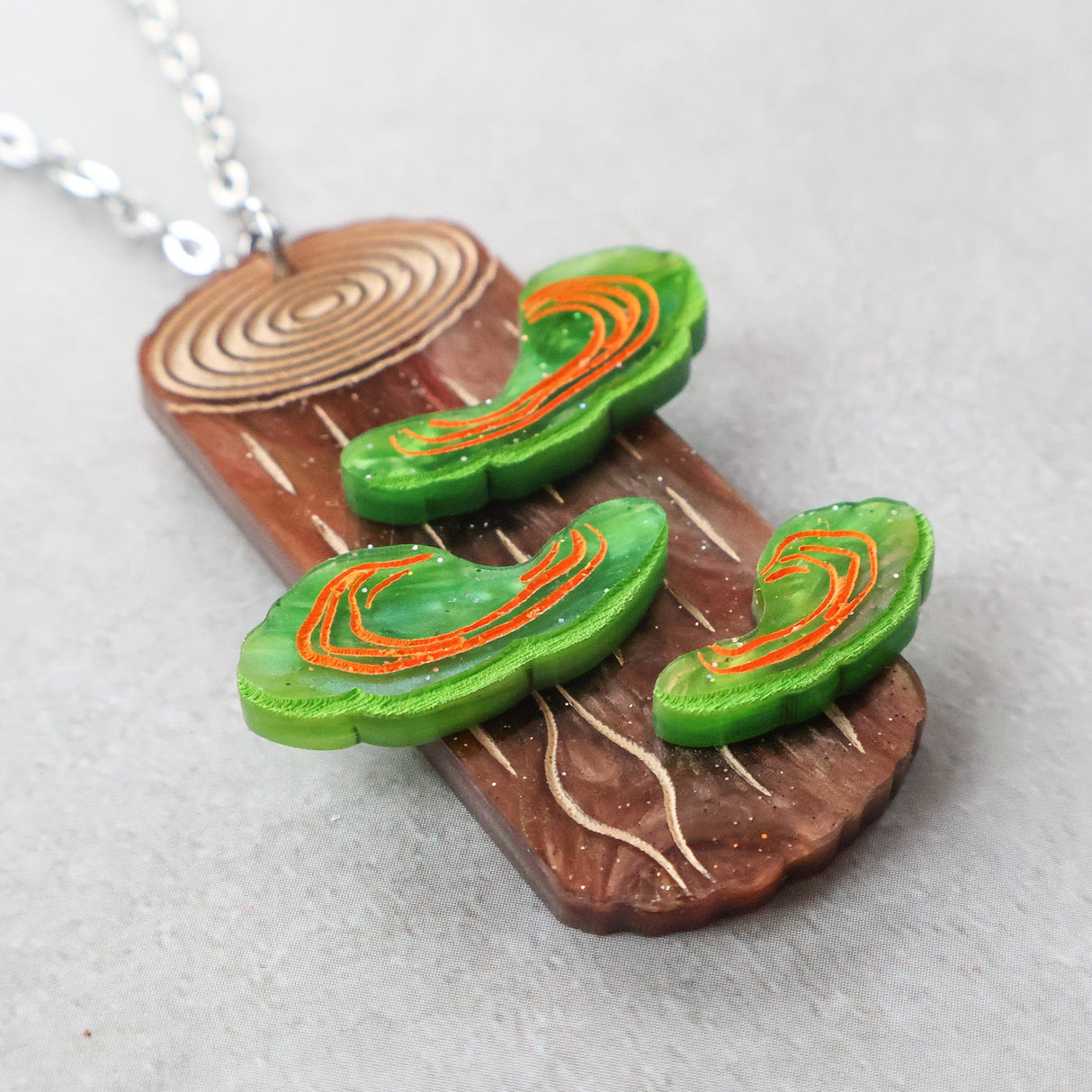 Acrylic pendant depicting polypore or shelf fungus growing from a tree trunk. Closeup Side view