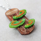 Acrylic pendant depicting polypore or shelf fungus growing from a tree trunk. Closeup Side view