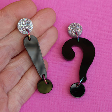 Asymmetrical punctuation mark earrings in hand showing a question and exclamation mark