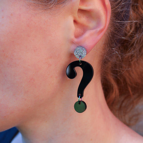 A woman modelling a pair of Question and exclamation mark earrings . Question mark side is shown in the photo. 