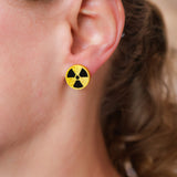Close-up of an ear wearing a yellow and black radiation symbol earring.