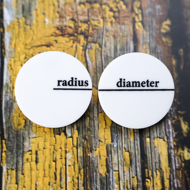 White asymmetrical acrylic studs with radius and diameter engraved and handpainted in black.