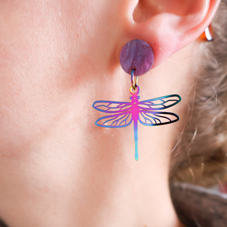 Close-up of an ear wearing a colorful dragonfly earring.