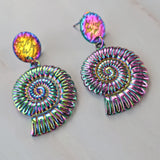 A pair of rainbow spiral nautilus shell earrings with stainless steel toppers. The rainbow effect is a stainless steel plating technique.