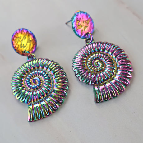 A pair of rainbow spiral nautilus shell earrings with stainless steel toppers. The rainbow effect is a stainless steel plating technique.