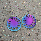 A pair of colourful rainbow toned stainless steel round earrings showing the phases of the moon, with french hooks.