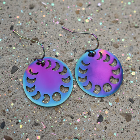 A pair of colourful rainbow toned stainless steel round earrings showing the phases of the moon, with french hooks.