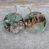 A pair of one of a kind disc shaped recycled acrylic earrings on stainless steel hoops with green and pink acrylics titled 'Enchanted Forest'. Pair 03-11