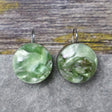 A pair of one of a kind round recycled acrylic earrings with stainless steel french hooks and green acrylics titled  'Green Ripple'. 