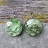 A pair of one of a kind round recycled acrylic earrings with stainless steel french hooks and green acrylics titled  'Green Ripple'. 