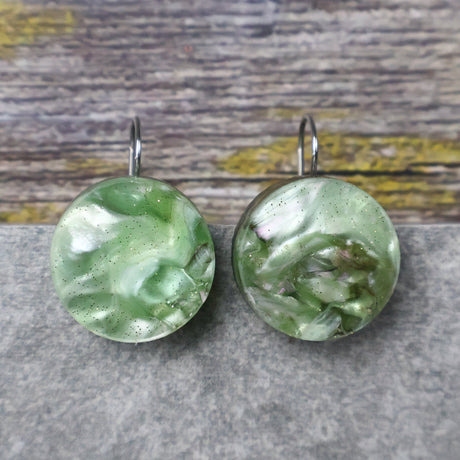 A pair of one of a kind round recycled acrylic earrings with stainless steel french hooks and green acrylics titled  'Green Ripple'. 