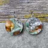 A pair of one of a kind round recycled acrylic earrings with stainless steel french hooks and green silver and brown acrylics titled  'Celestial Tide'. 