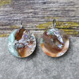 A pair of one of a kind round recycled acrylic earrings with stainless steel french hooks and green silver and brown acrylics titled  'Celestial Tide'. 