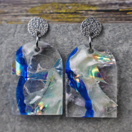 A pair of one of a kind arch shaped recycled acrylic earrings with blue, clear and pearlescent acrylics titled  'Aurora Shards' and stainless steel toppers. Pair 100-02