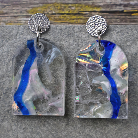 A pair of one of a kind arch shaped recycled acrylic earrings with blue, clear and pearlescent acrylics titled  'Aurora Shards' and stainless steel toppers. Pair 100-04