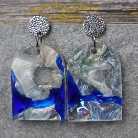 A pair of one of a kind arch shaped recycled acrylic earrings with blue, clear and pearlescent acrylics titled  'Aurora Shards' and stainless steel toppers. Pair 100-05