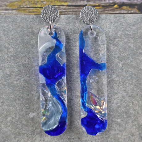 A pair of one of a kind long oval shaped recycled acrylic earrings with blue, clear and pearlescent acrylics titled  'Aurora Shards' and stainless steel toppers. Pair 100-08