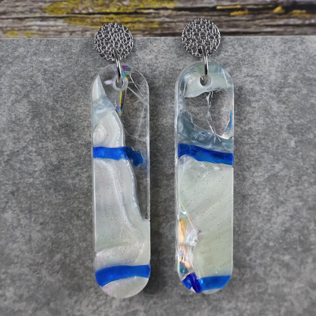 A pair of one of a kind long oval shaped recycled acrylic earrings with blue, clear and pearlescent acrylics titled  'Aurora Shards' and stainless steel toppers. Pair 100-09
