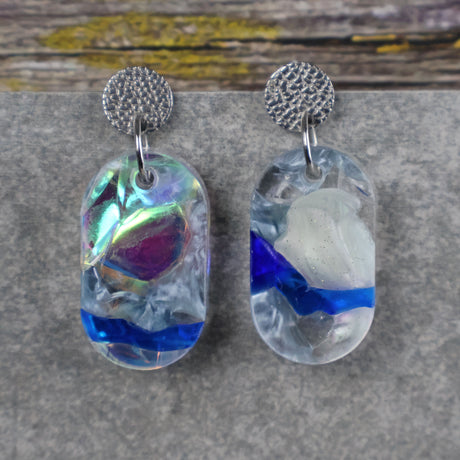 A pair of one of a kind oval shaped recycled acrylic earrings with blue, clear and pearlescent acrylics titled  'Aurora Shards' and stainless steel toppers. Pair 100-10