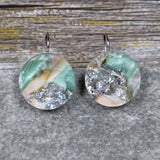 A pair of one of a kind round recycled acrylic earrings with stainless steel french hooks and silver, green and brown design titled 'Celestial Tide' Pair 106-15