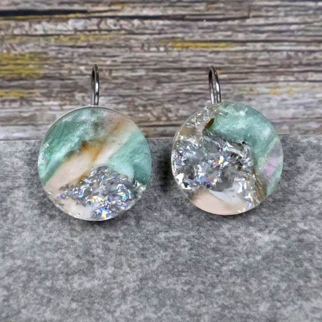 A pair of one of a kind round recycled acrylic earrings with stainless steel french hooks and silver, green and brown design titled 'Celestial Tide' Pair 106-15