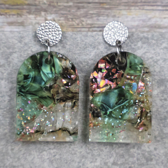 A pair of one of a kind arch shaped recycled acrylic earrings with green and pink design titled 'Enchanted Forest' and stainless steel toppers. Pair 103-05