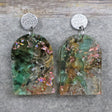 A pair of one of a kind arch shaped recycled acrylic earrings with green and pink design titled 'Enchanted Forest' and stainless steel toppers. Pair 103-04