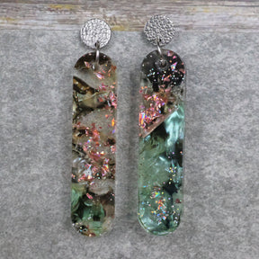 A pair of one of a kind long oval shaped recycled acrylic earrings with green and pink design titled 'Enchanted Forest' and stainless steel toppers. Pair 103-13