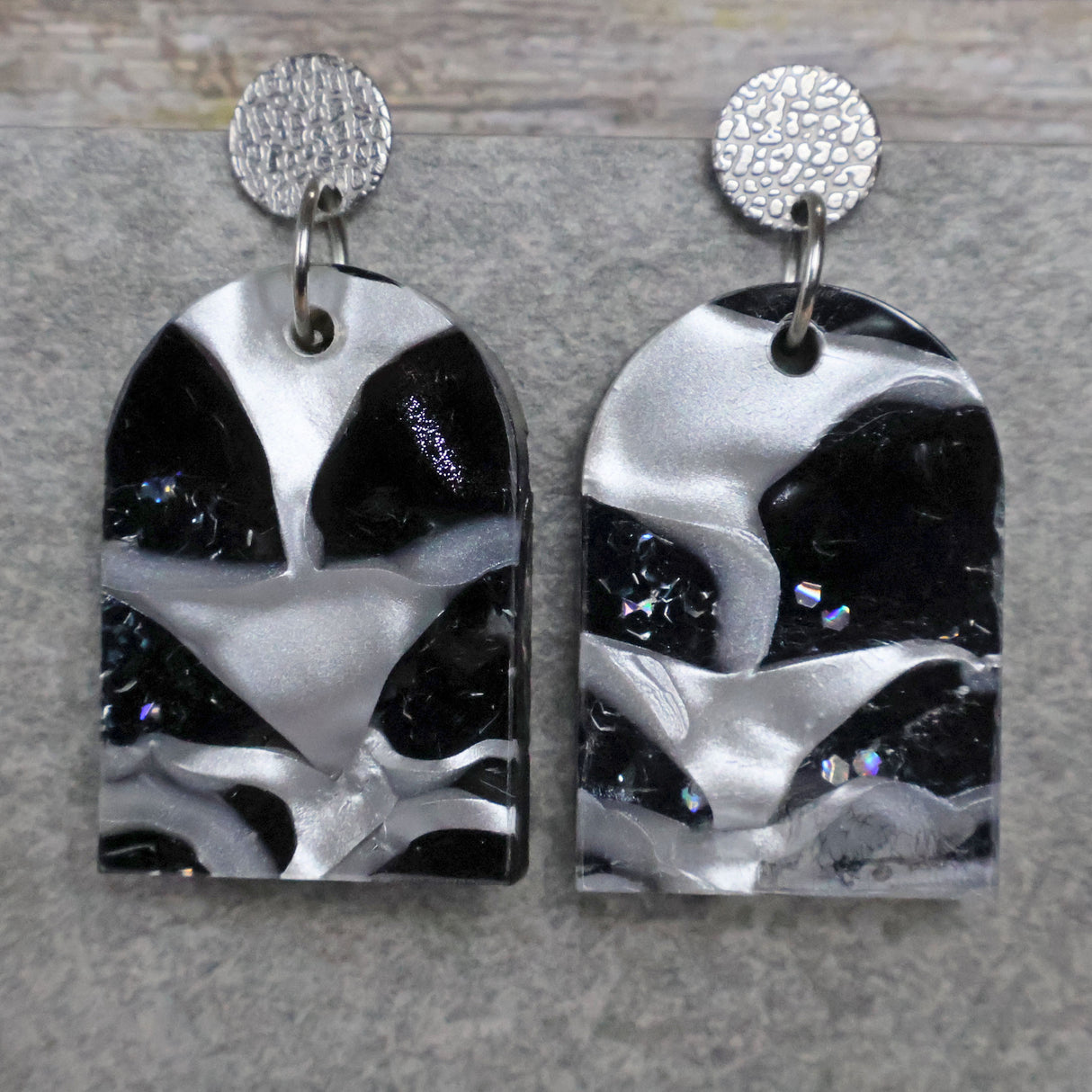 A pair of one of a kind arch shaped recycled acrylic earrings with black and white design titled 'Lunar Edge' and stainless steel toppers. Pair 104-02